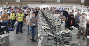 Around twenty people wearing face coverings in a room containing a twenty ventilators